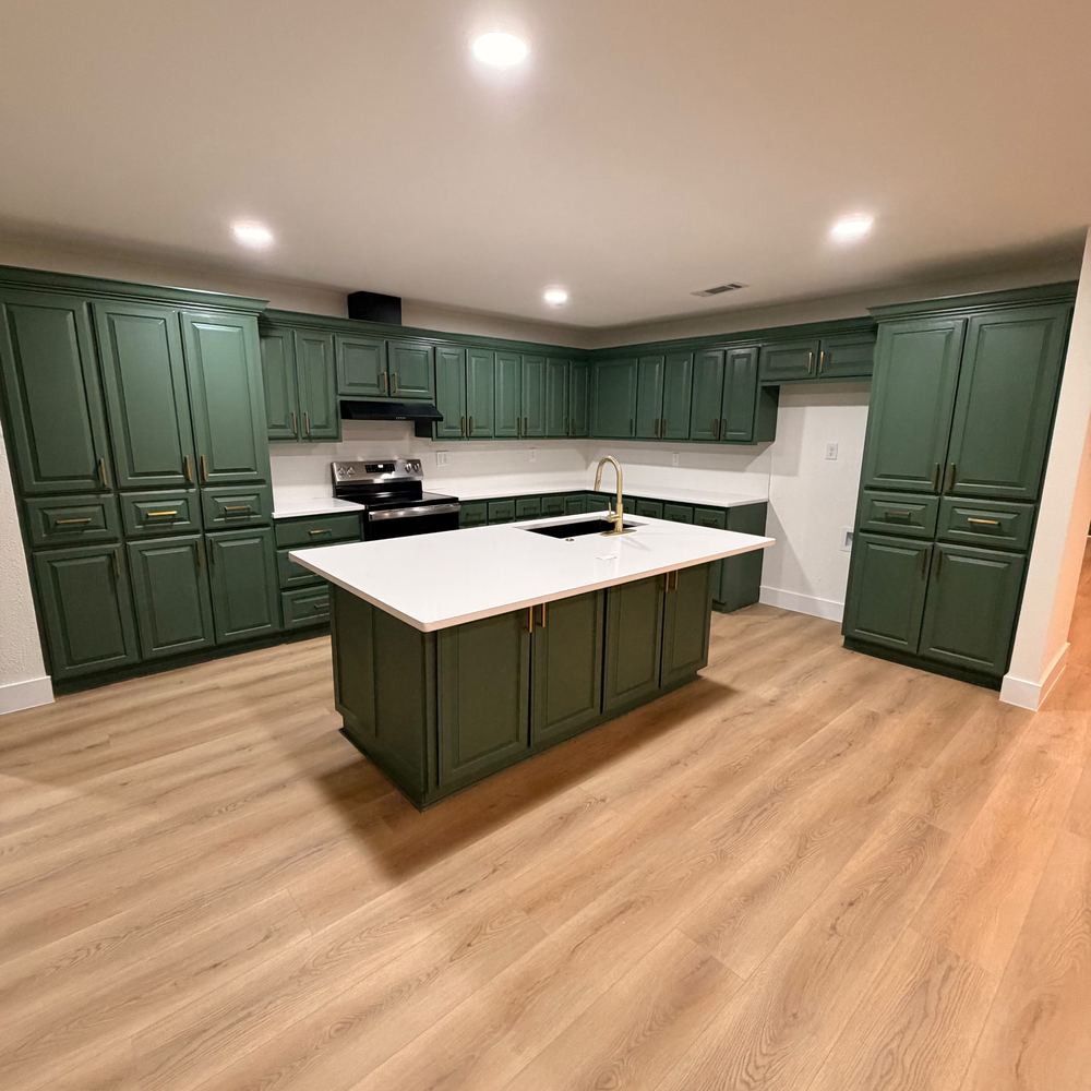 Cocina con gabinetes verdes e isla de cuarzo